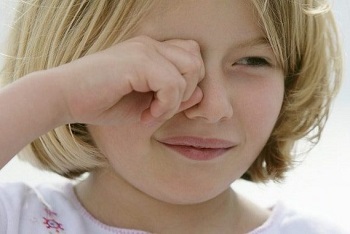 Светловолосая девочка трет глаза