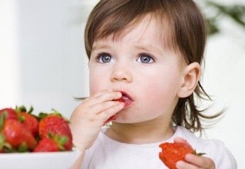 Девочка ест спелую ягоду