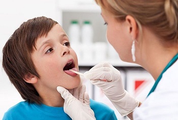 Мальчику осматривают горло