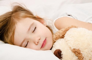 Девочка спит с мягкой игрушкой